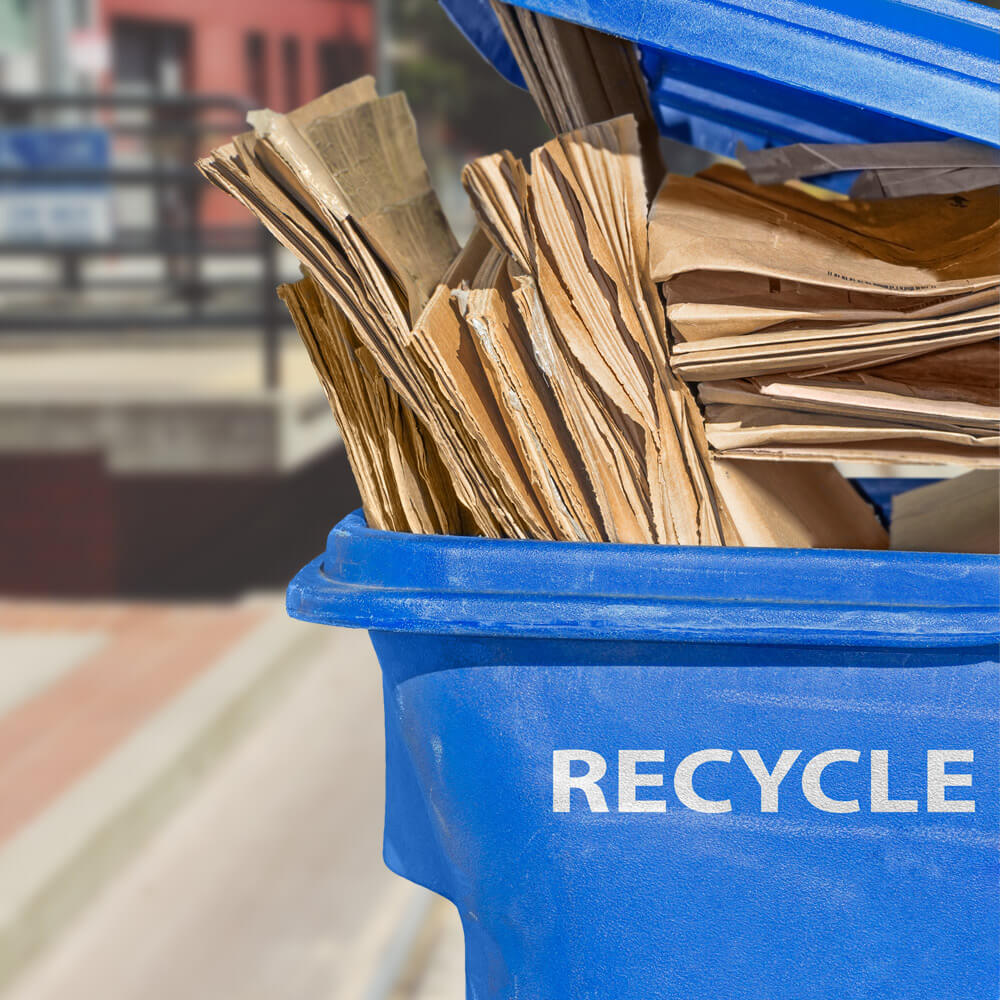 flattened cardboard boxes placed in a blue container marked "recycle"