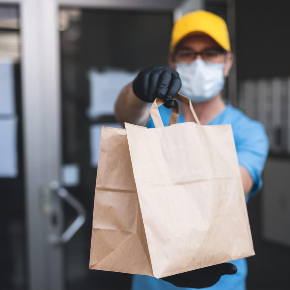 person with mask holding a paper bag